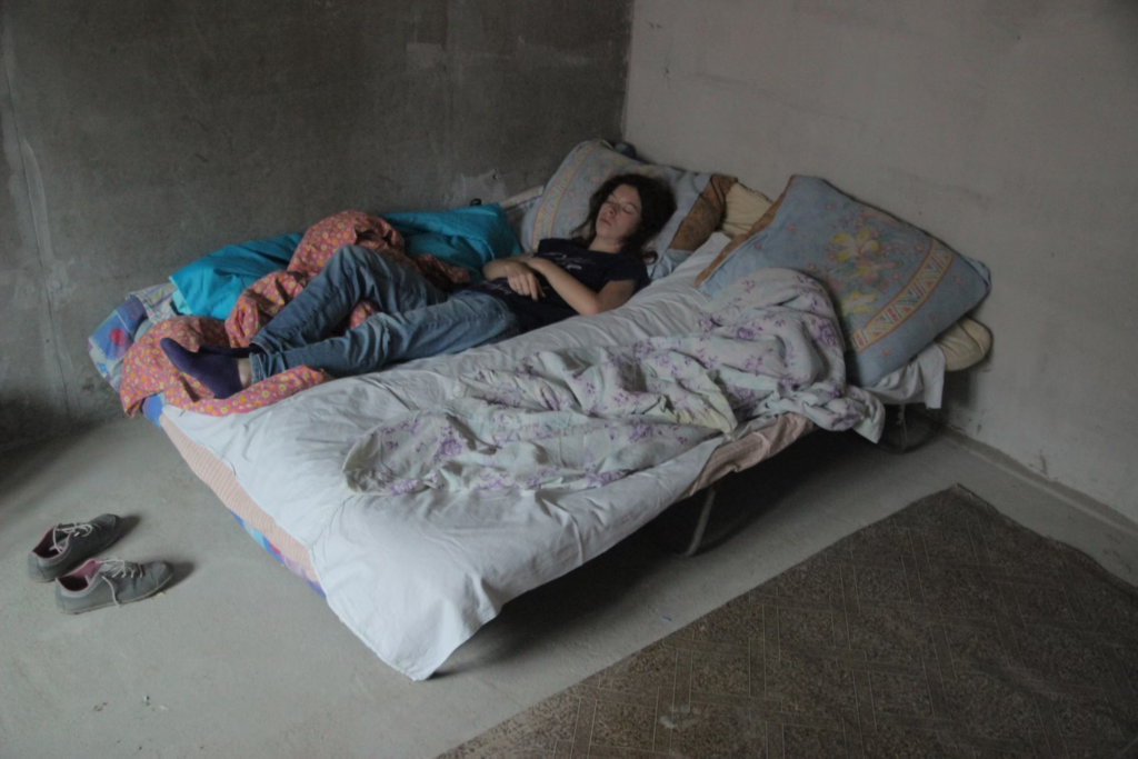 A woman peacefully sleeping on a bed, surrounded by a cozy room, while her partner is absent.