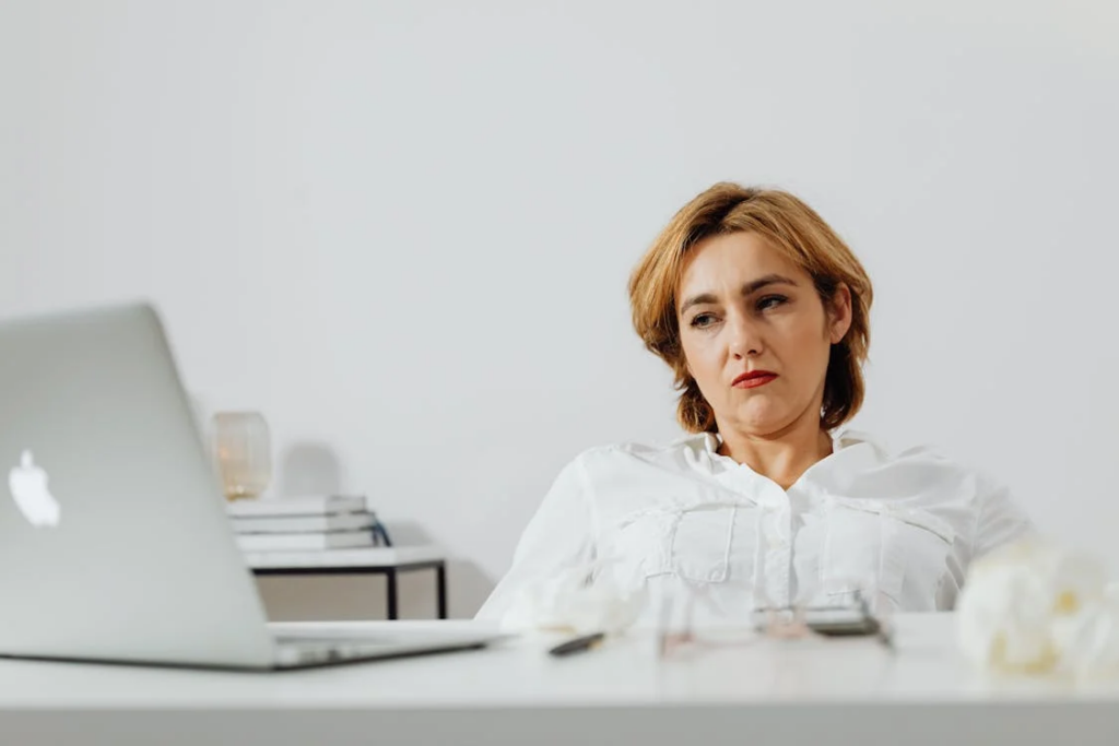 A woman at her desk with a laptop, showing signs of low motivation, which can be an early indicator of dementia.