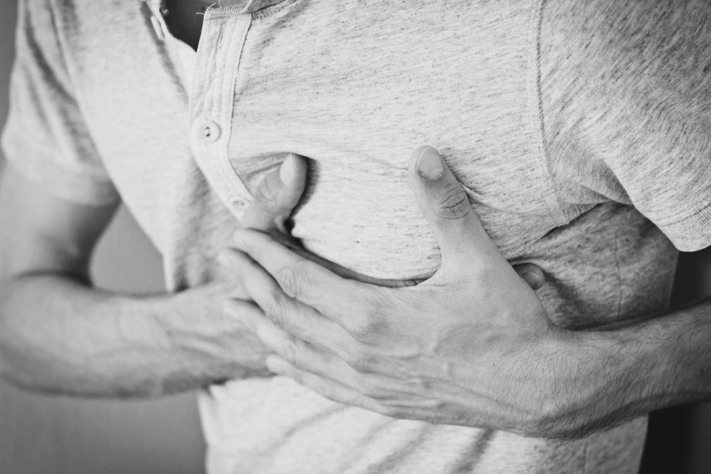 Man clutching chest experiencing sudden heart attack symptoms.