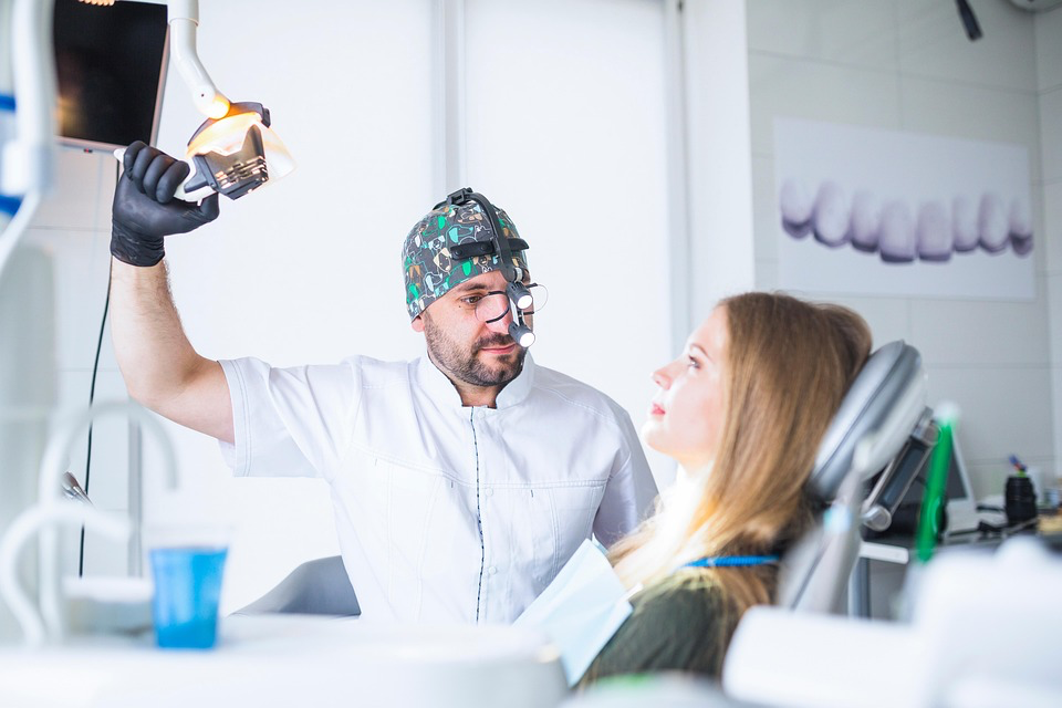Dentist examining patient's teeth, showing the connection between oral health and preventing sign of heart attack.