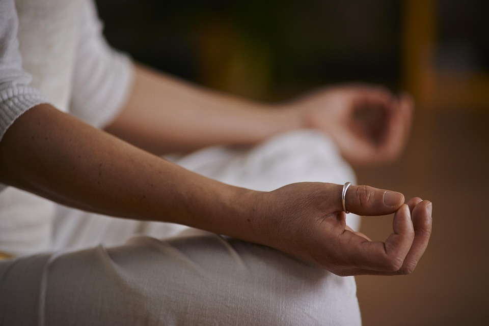 Woman practicing meditation with hands in peaceful position to manage stress.