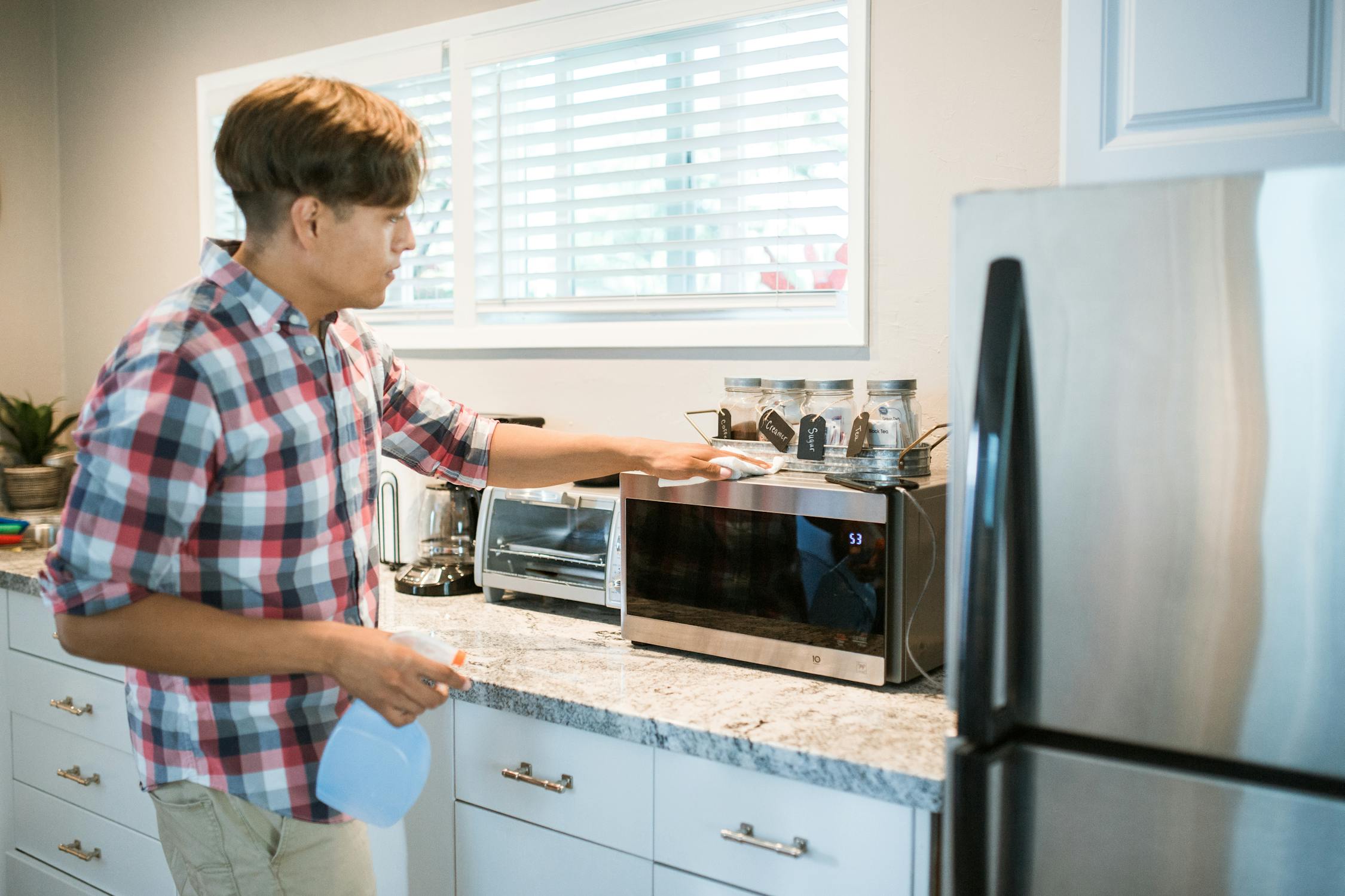 A Man Wiping a Microwave Oven