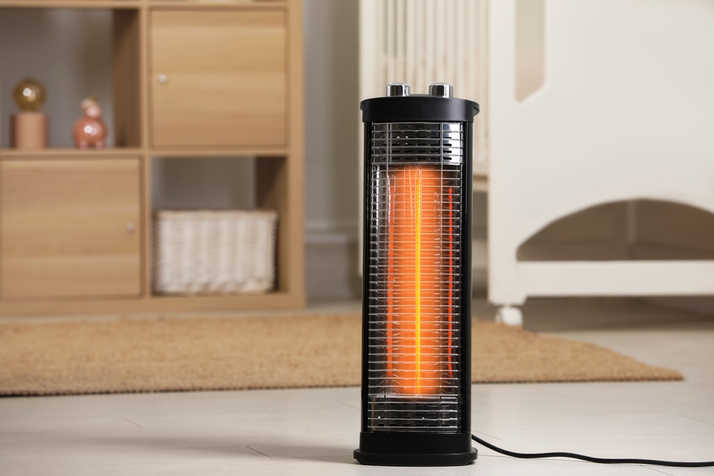 Modern infrared heater on floor in cozy room. Space for text
